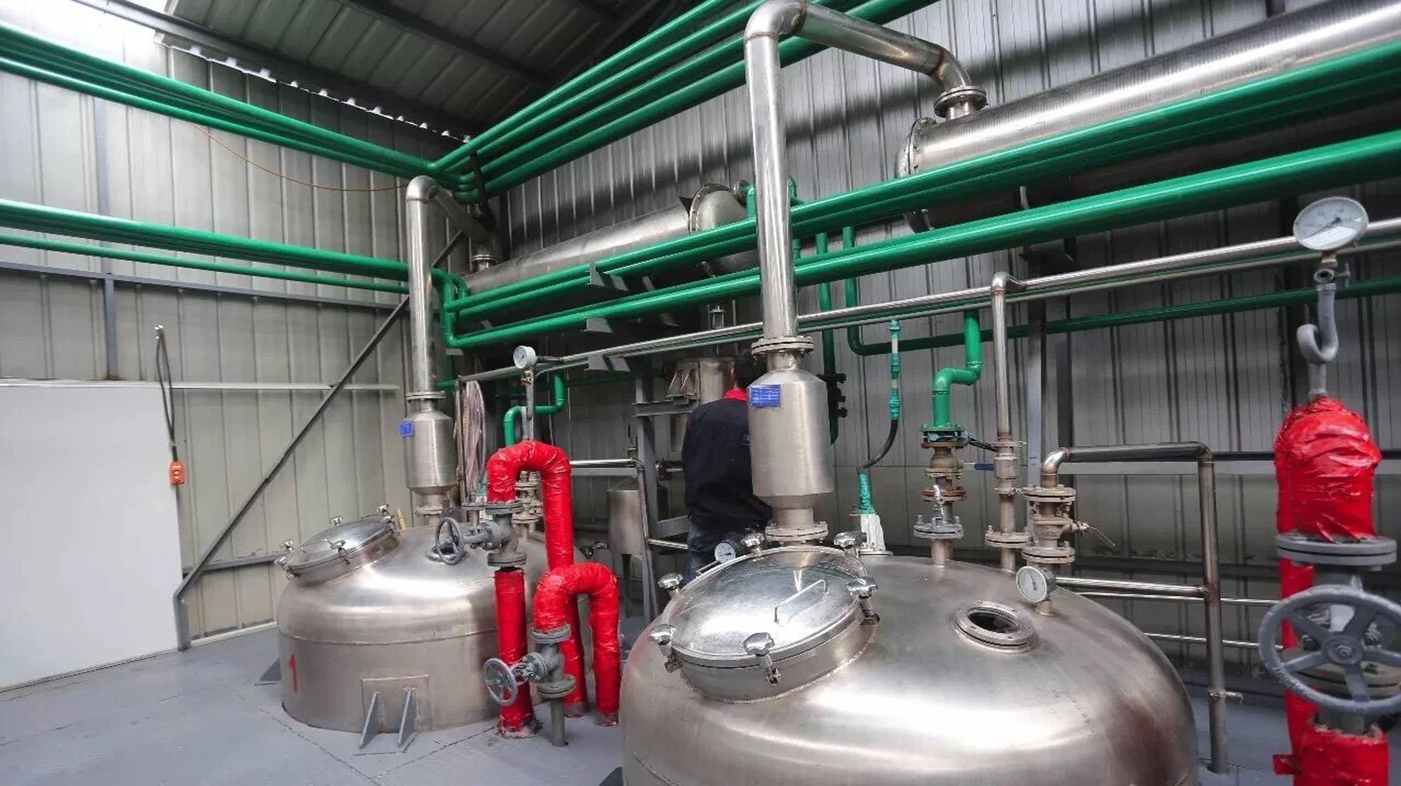 Botanical extraction workshop - stainless steel reactors with green piping for herbal extraction processing
